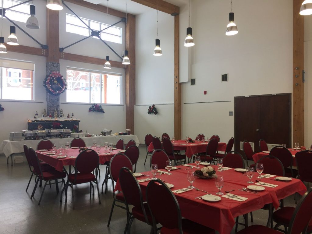Salle communautaire montée avec tables et chaises à Noël